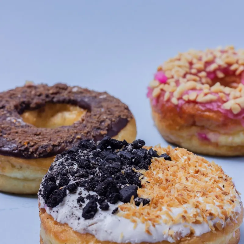 Mini crispy donut half-dipped in rich chocolate dip with drip runs